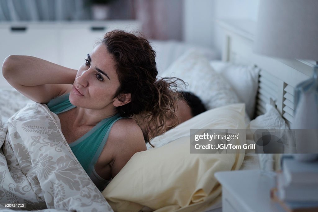 Woman rubbing her neck in bed