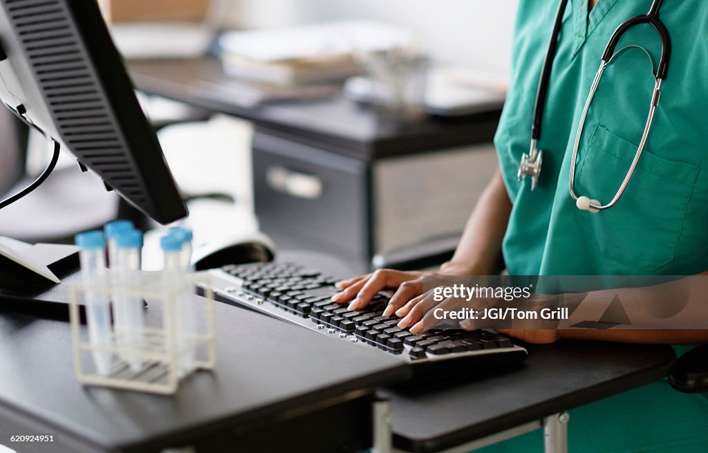 Mixed race nurse working at computer