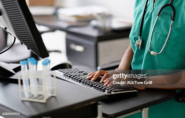 mixed race nurse working at computer - administrator bildbanksfoton och bilder