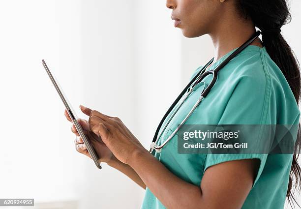 mixed race nurse using digital tablet - data privacy day stock pictures, royalty-free photos & images