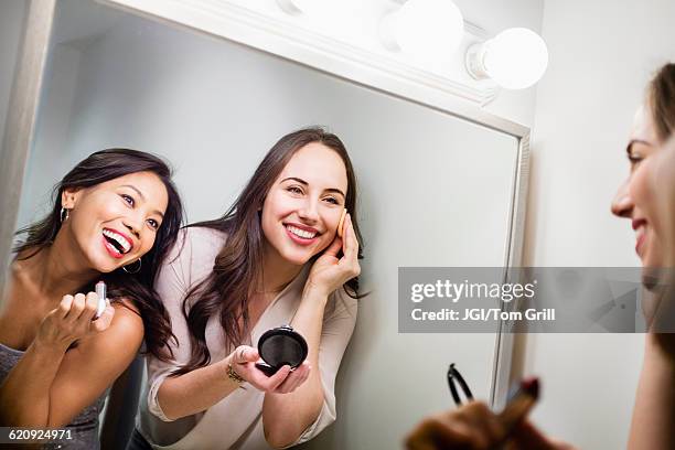 women applying makeup in mirror - friends women makeup stockfoto's en -beelden
