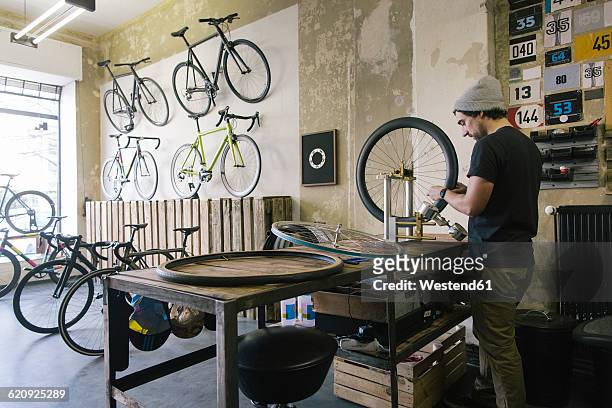 mechanic working on tire in a custom-made bicycle store - loja de bicicletas imagens e fotografias de stock