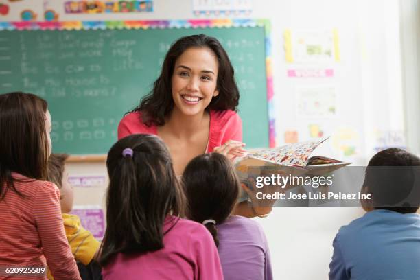 mixed race teacher reading to students - spelling stock photos et images de collection