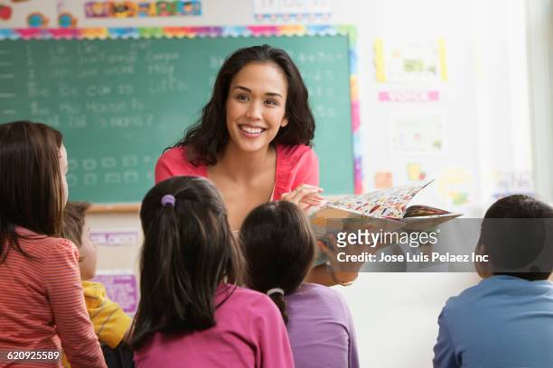 mixed race teacher reading to students - elementary school classroom stockfoto's en -beelden