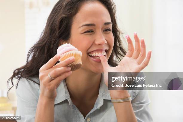 mixed race woman eating cupcake - manger sur le pouce photos et images de collection