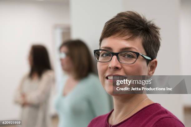 businesswoman smiling in office - mid adult women stock pictures, royalty-free photos & images