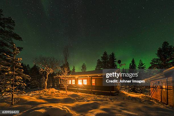 aurora borealis and stars above log house - sweden winter stock pictures, royalty-free photos & images