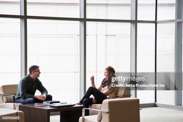 caucasian business people talking in office lounge - office sofa stock-fotos und bilder