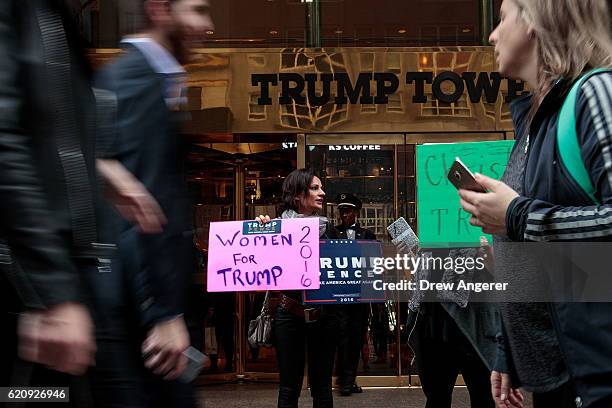 Supporters of Republican presidential candidate Donald Trump stand outside of Trump Tower as pedestrians pass by, November 3, 2016 in New York City....