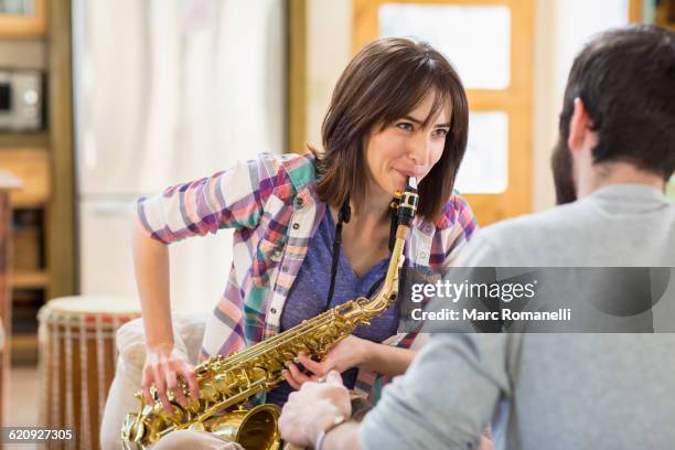 hispanic man watching girlfriend playing saxophone - guy loving music jazz stock-fotos und bilder