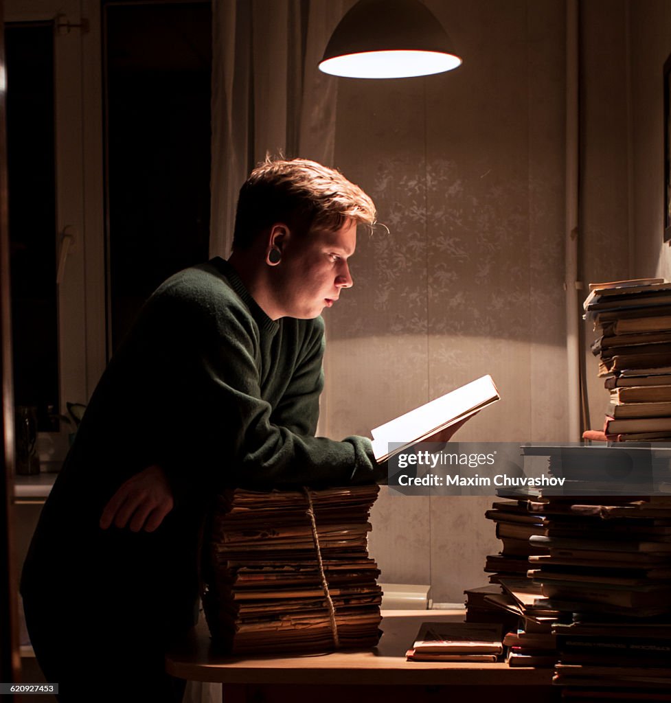 Caucasian man reading stack of books