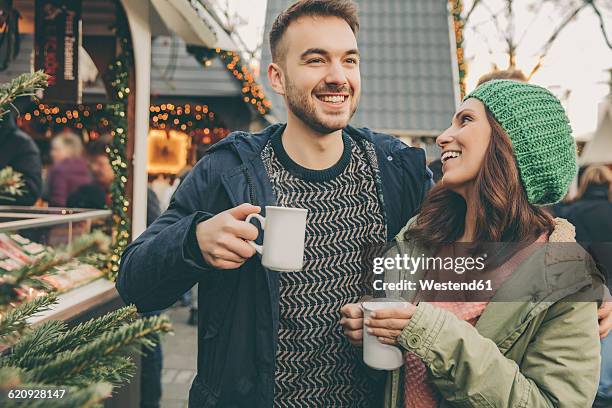 couple having a hot punch on the christmas market - punsch tasse stock-fotos und bilder