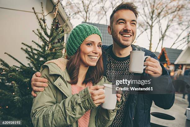 couple having a hot punch on the christmas market - ponche fotografías e imágenes de stock