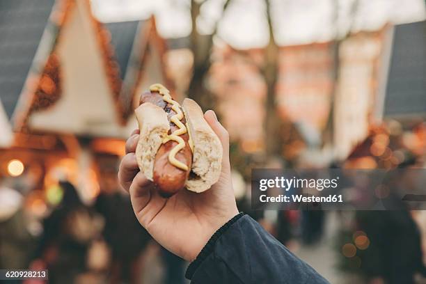 hand of a man holding a bratwurst on the christmas market - bratwurst stock pictures, royalty-free photos & images