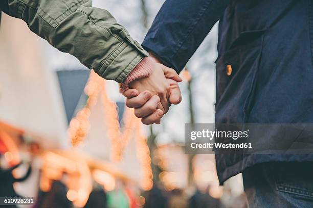 close-up of couple holding hands on the christmas market - holding hands close up stock-fotos und bilder