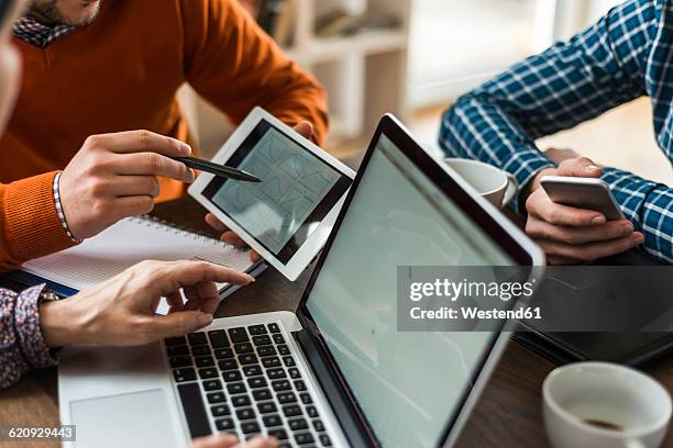 colleagues at desk looking at digital tablet showing different shapes - multiple devices stock-fotos und bilder