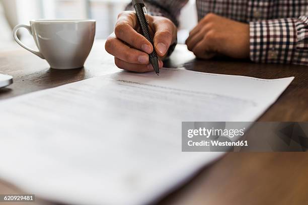 close-up of man signing document on table - human body part stock pictures, royalty-free photos & images