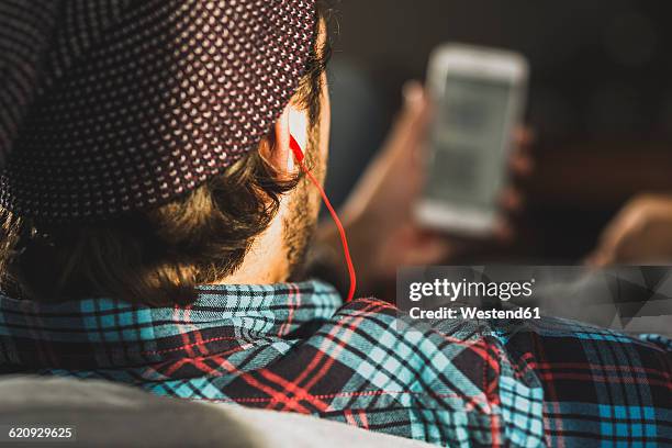 back view of man hearing music with earphones, close-up - mp3 player stock-fotos und bilder