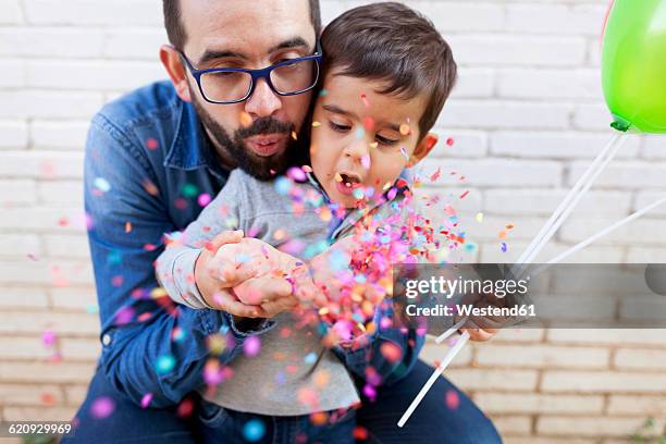 father and his little son blowing confetti - familienfeier stock-fotos und bilder