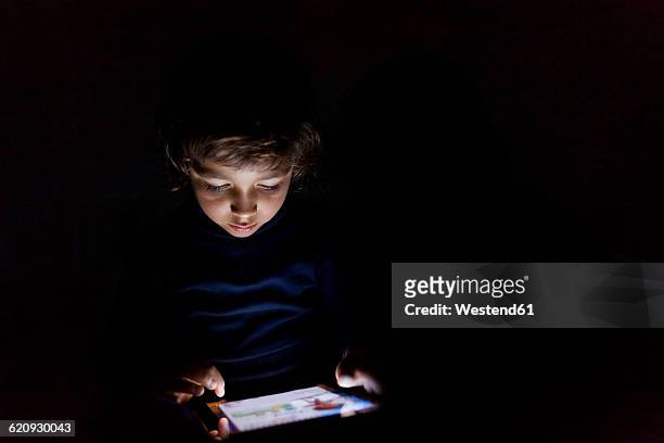 little boy in darkness playing with digital tablet - high contrast bildbanksfoton och bilder