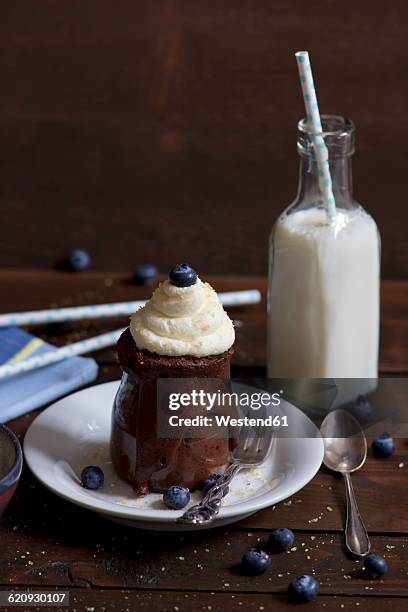 chocolate cake in a glass with whipped cream, cane sugar and blueberries and a bottle of milk - chocolate milk bottle stock pictures, royalty-free photos & images