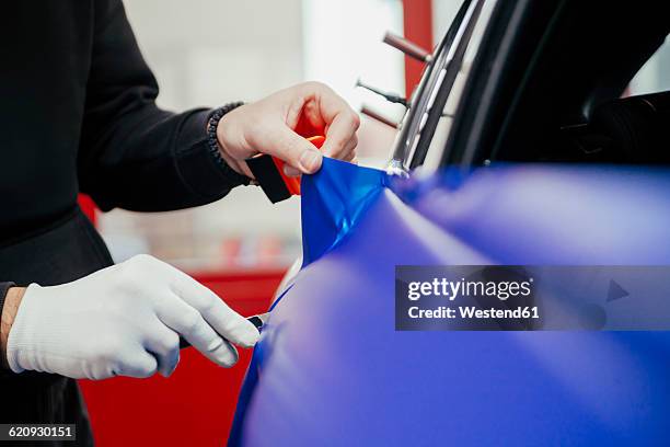 man wrapping car with vinyl foil - vinyl car wrap fotografías e imágenes de stock