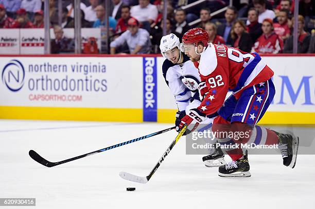 Evgeny Kuznetsov of the Washington Capitals skates with the puck against Alexander Burmistrov of the Winnipeg Jets in the second period during a NHL...