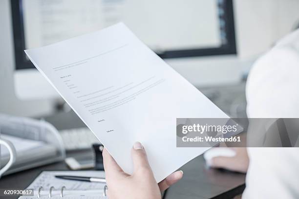 close-up of woman at desk holding a document - human role imagens e fotografias de stock