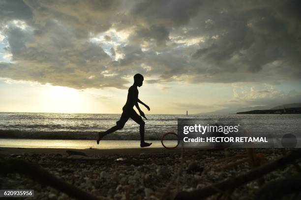 Boy plays on a beached damaged by Hurricane Matthew, in the commune of Port-a-Piment, in the southwestern Haiti, on November 3, 2016. At least 546...