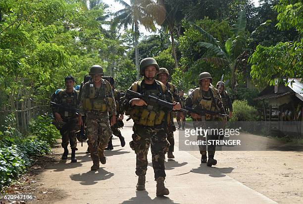 This photo taken on August 26, 2016 shows Philippine soldiers walking along a highway as they return to camp at the village of Bongkaong, Patikul...