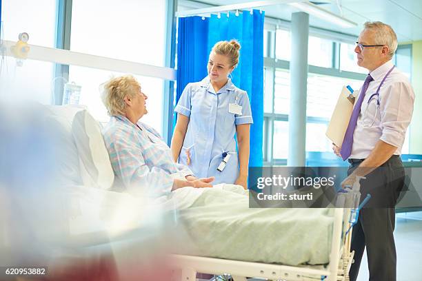 senior hospital patient chatting to doc and nurse - postoperatief stockfoto's en -beelden