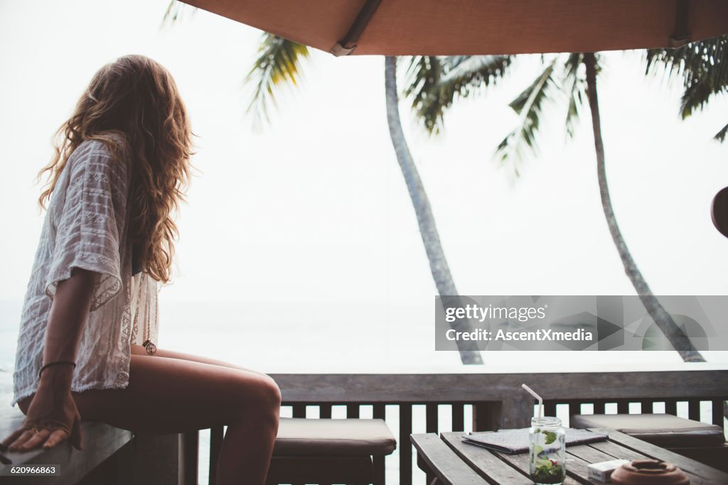 Young woman relaxes at beachside cafe