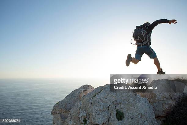 hiker leaps between boulders on summit - republik zypern stock-fotos und bilder