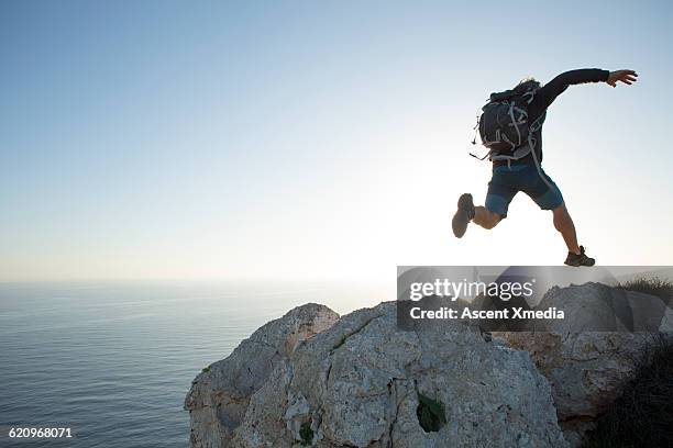 hiker leaps between boulders on summit - republic of cyprus fotografías e imágenes de stock