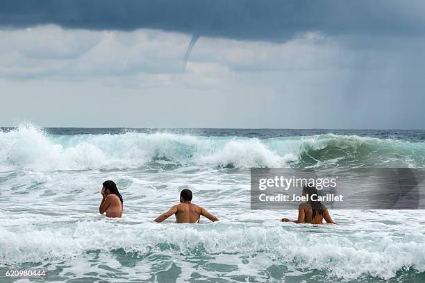 waterspout and people at beach in zipolite, mexico - bare beach stock pictures, royalty-free photos & images