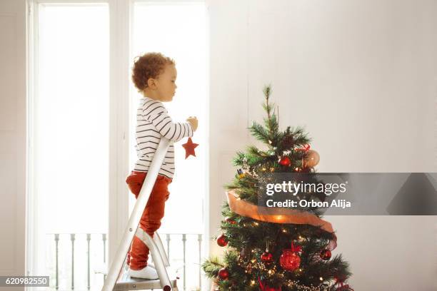 boy decorating christmas tree - tree topper stock pictures, royalty-free photos & images