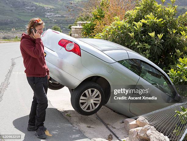 young man talks on phone beside car accident - unfall stock-fotos und bilder