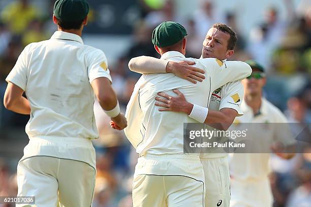 Peter Siddle and Shaun Marsh of Australia embrace after dismissing Stephen Cook of South Africa during day two of the First Test match between...