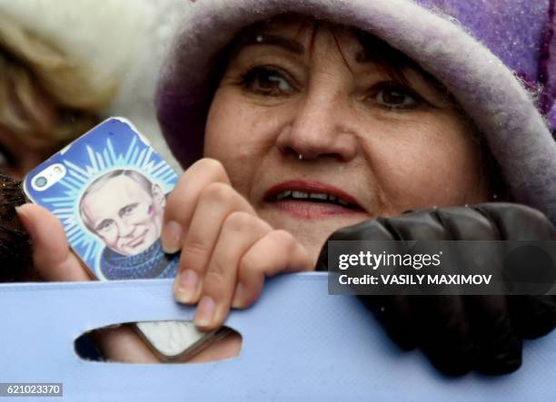 Woman holds a smartphone bearing an image of Russian President Vladimir Putin as Pro-Kremlin supporters march in central Moscow on November 4, 2016...