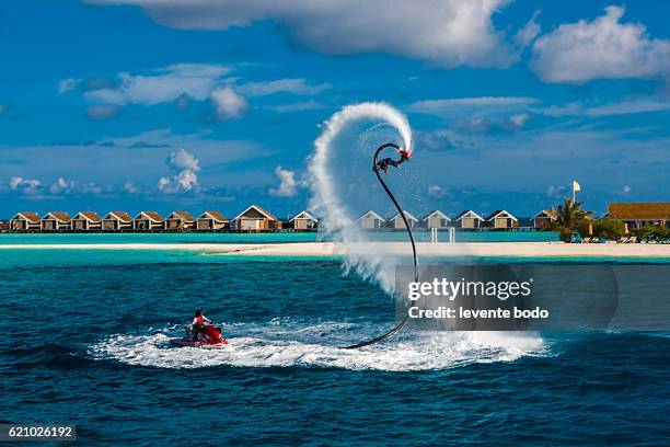 fly board and jet ski in the blue lagoon. silhouette of a fly board rider at sea. professional rider is playing with a new water sport called fly board. tropical summer water-sport activity. - hover board ストックフォトと画像