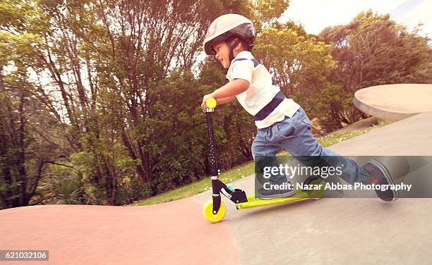 kid on his push scooter in skateboard park. - kinder kickboard stock-fotos und bilder