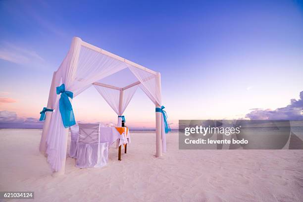 romantic luxury dinner setting at tropical beach on sunset - private dining stock pictures, royalty-free photos & images