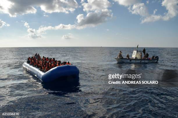 Migrants and refugees sit on a rubber boat as the Libyan coastguards patrol, during a rescue operation of the Topaz Responder, a rescue ship run by...