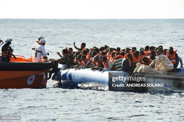 Migrants and refugees sit on a rubber boat during a rescue operation of the Topaz Responder, a rescue ship run by Maltese NGO "Moas" and the Italian...