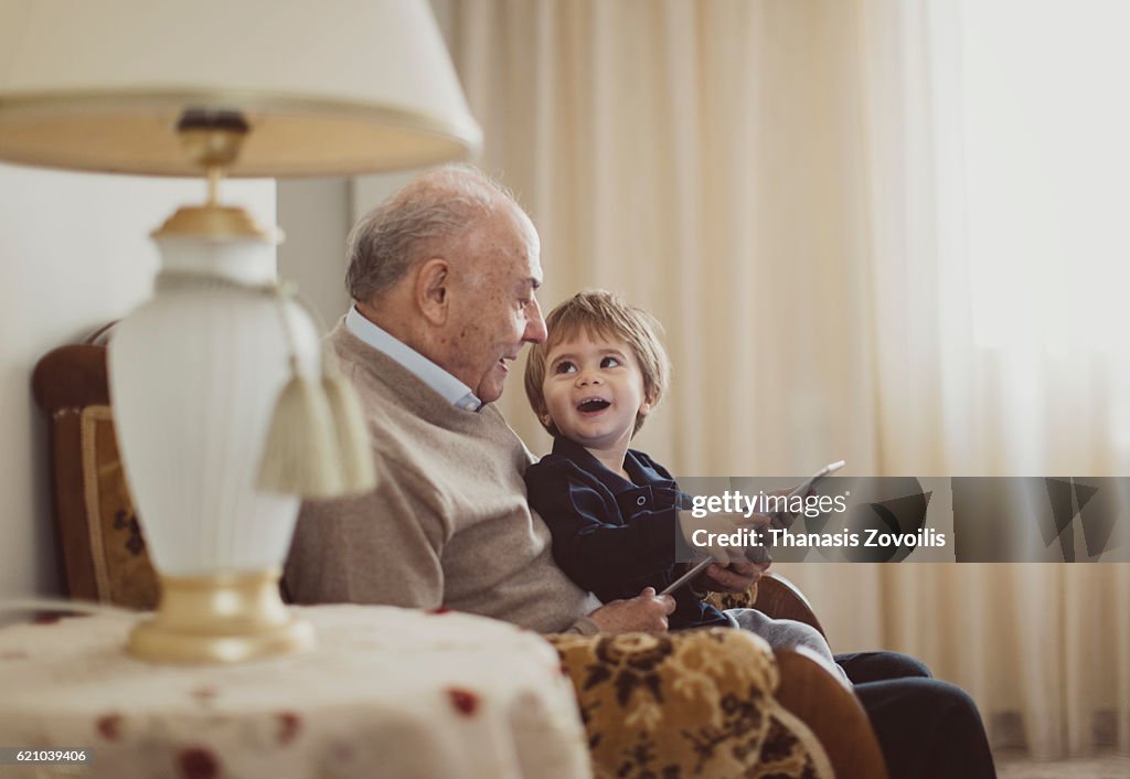 Grandfather with his grandson using a digital tablet