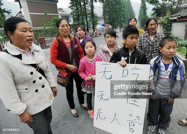 China - People show reporters a message reading "We have no food or housing and no one is taking care of us" in Lushan county in Ya'an, in the...