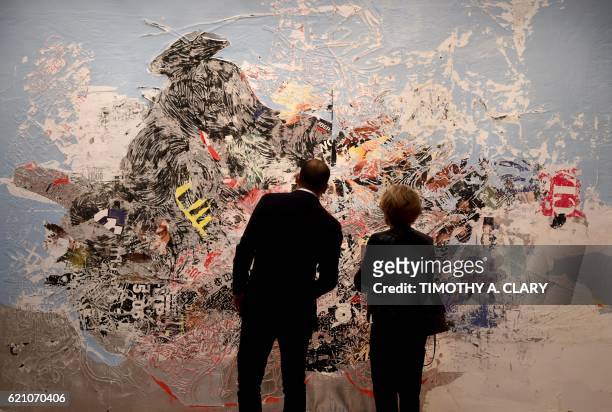 People look at Mark Bradford's "Let's Make Christmas Mean Something This Year" on display during the media preview on November 4, 2016 for Sotheby's...
