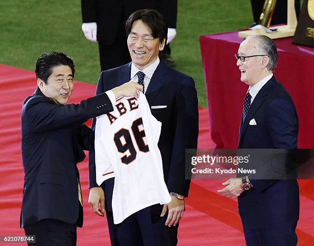 Japan - Prime Minister Shinzo Abe receives a jersey with No. 96 as a gift from former professional baseball players Hideki Matsui and Shigeo...