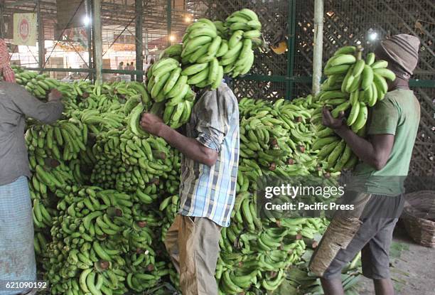 Laborers unload bananas from truck ahead of Hindu Vedic festival dedicated to the Hindu Sun God "Chhath Puja" at wholesale market Mundera Mandi.