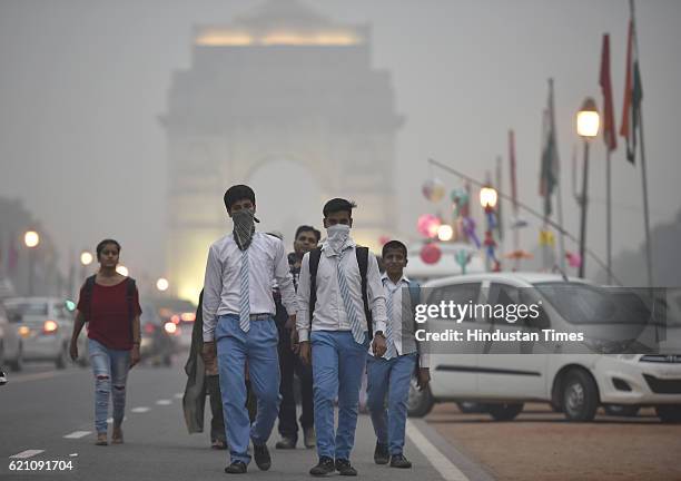 School students covers their face with a handkerchief to avoid thick smog at Janpath Market in the evening, as the air quality deteriorated sharply...